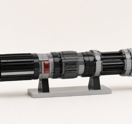 Generyczna klockowa rękojeść sci-fi w czerni i szarościach z małym czerwonym przezroczystym detalem, ustawiona na prostej podstawce na jasnym neutralnym tle.