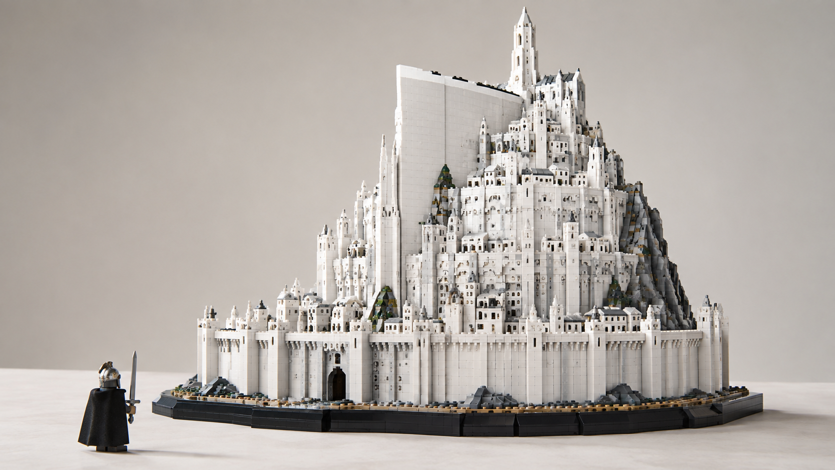 Symboliczna klockowa interpretacja białego, wielopoziomowego Minas Tirith na neutralnym tle, z pojedynczą postacią na pierwszym planie dla pokazania skali.